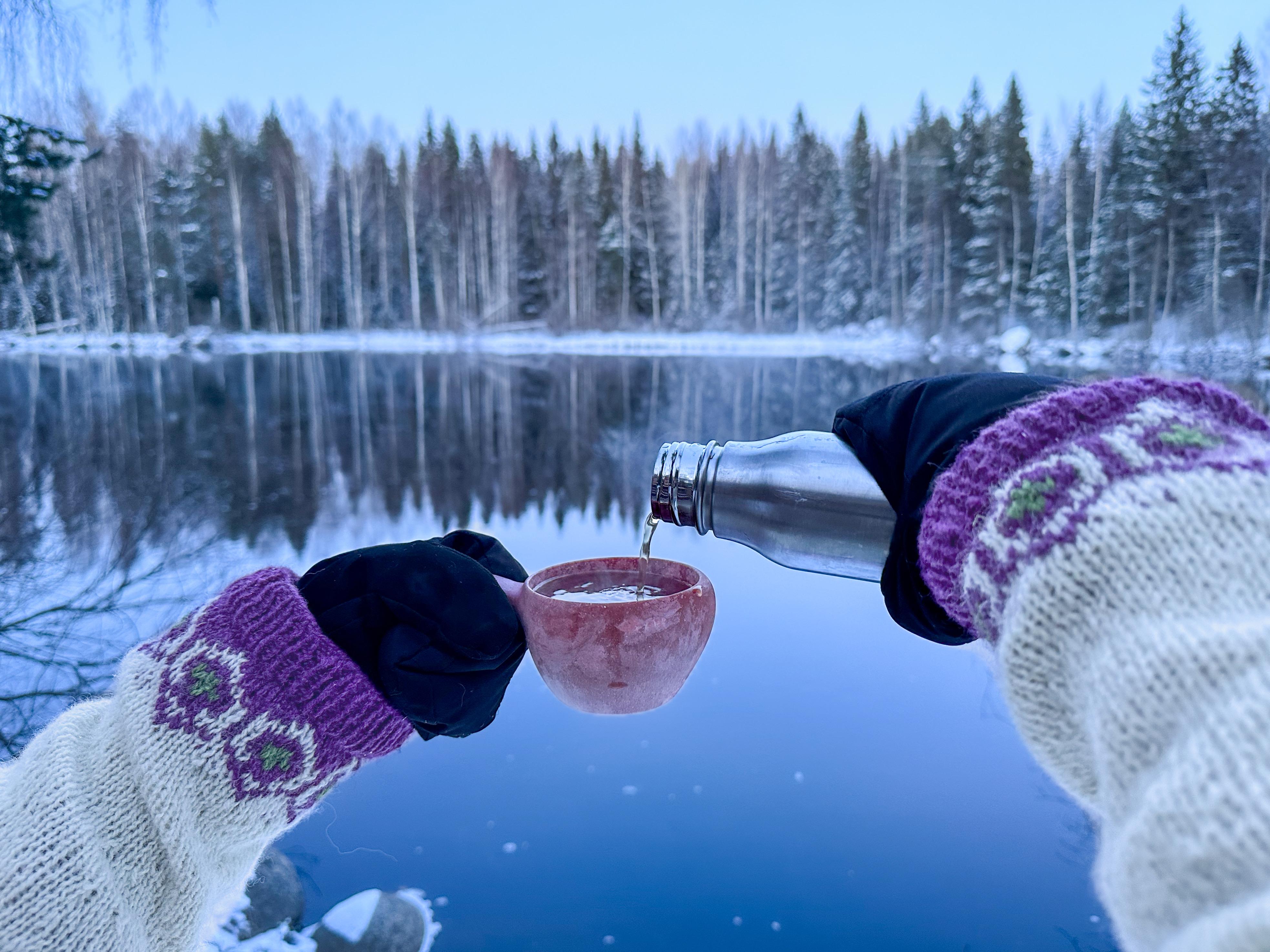 Koskimaisemassa nautitaan teetä kuksasta
