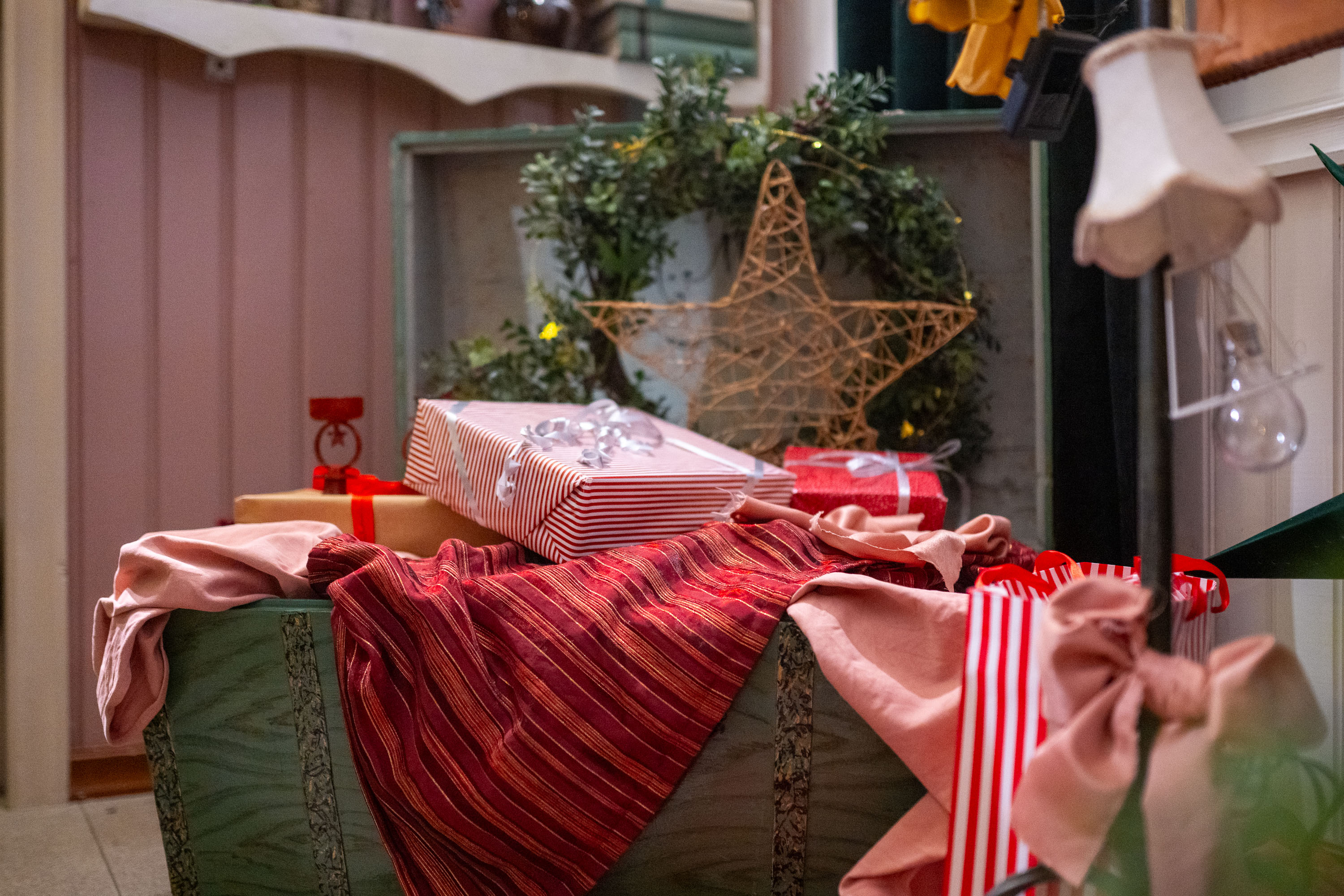 Puuarkussa lahjapaketteja ja kranssi kankaiden päällä.