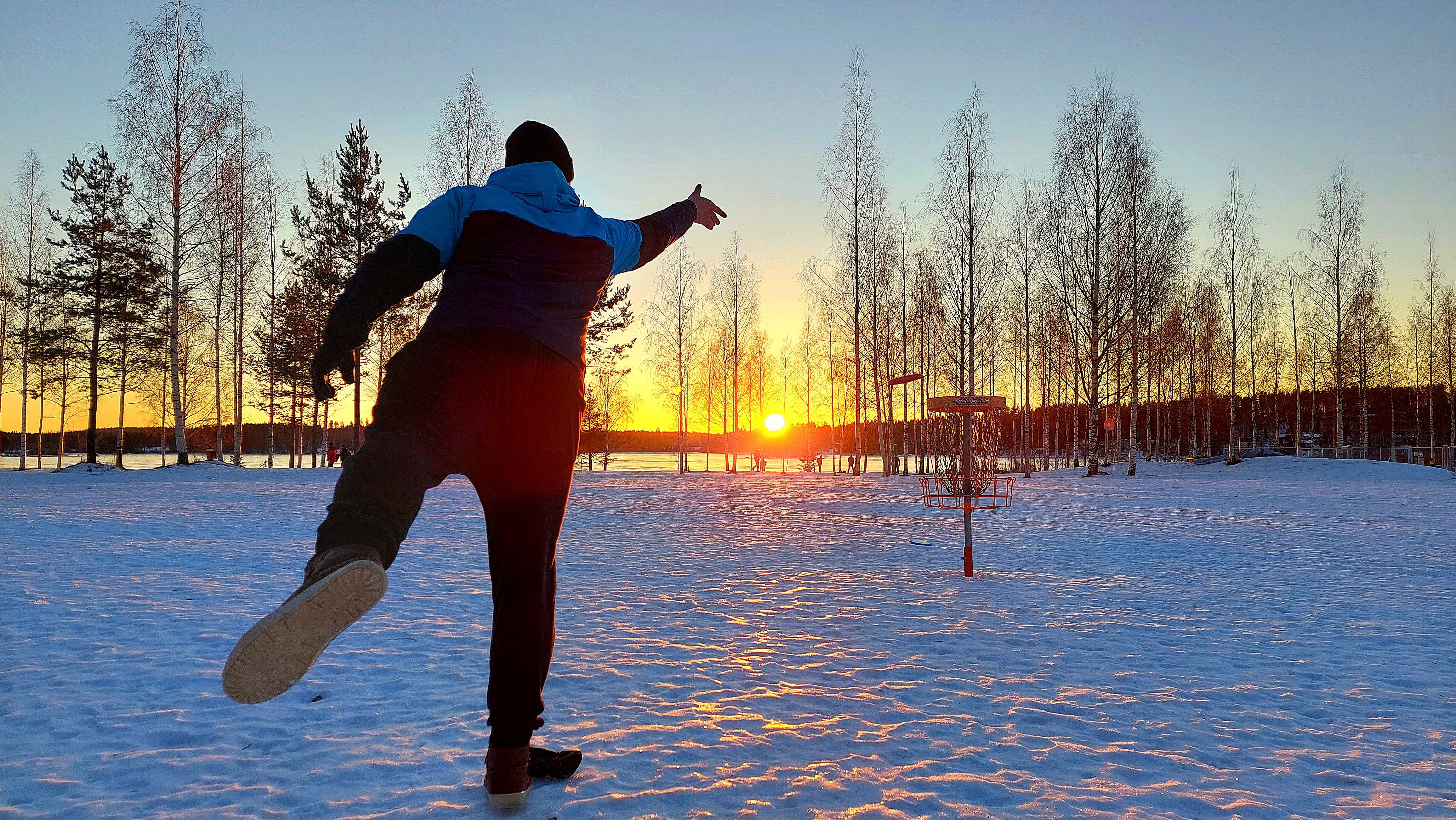 Henkilö heittää talvella frisbeegolfia.
