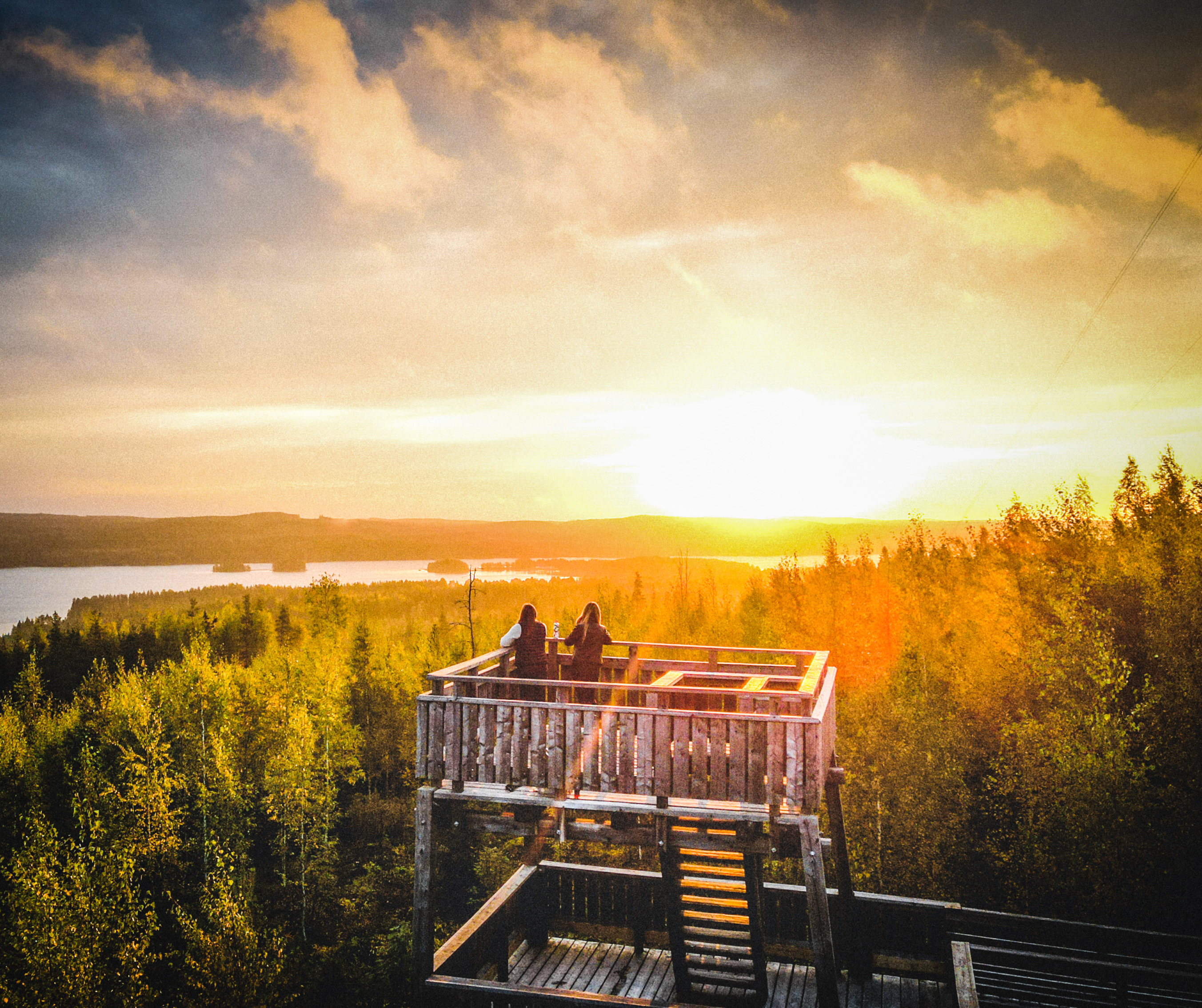 Kaksi ihmistä näkötornissa katsomassa auringonnousua