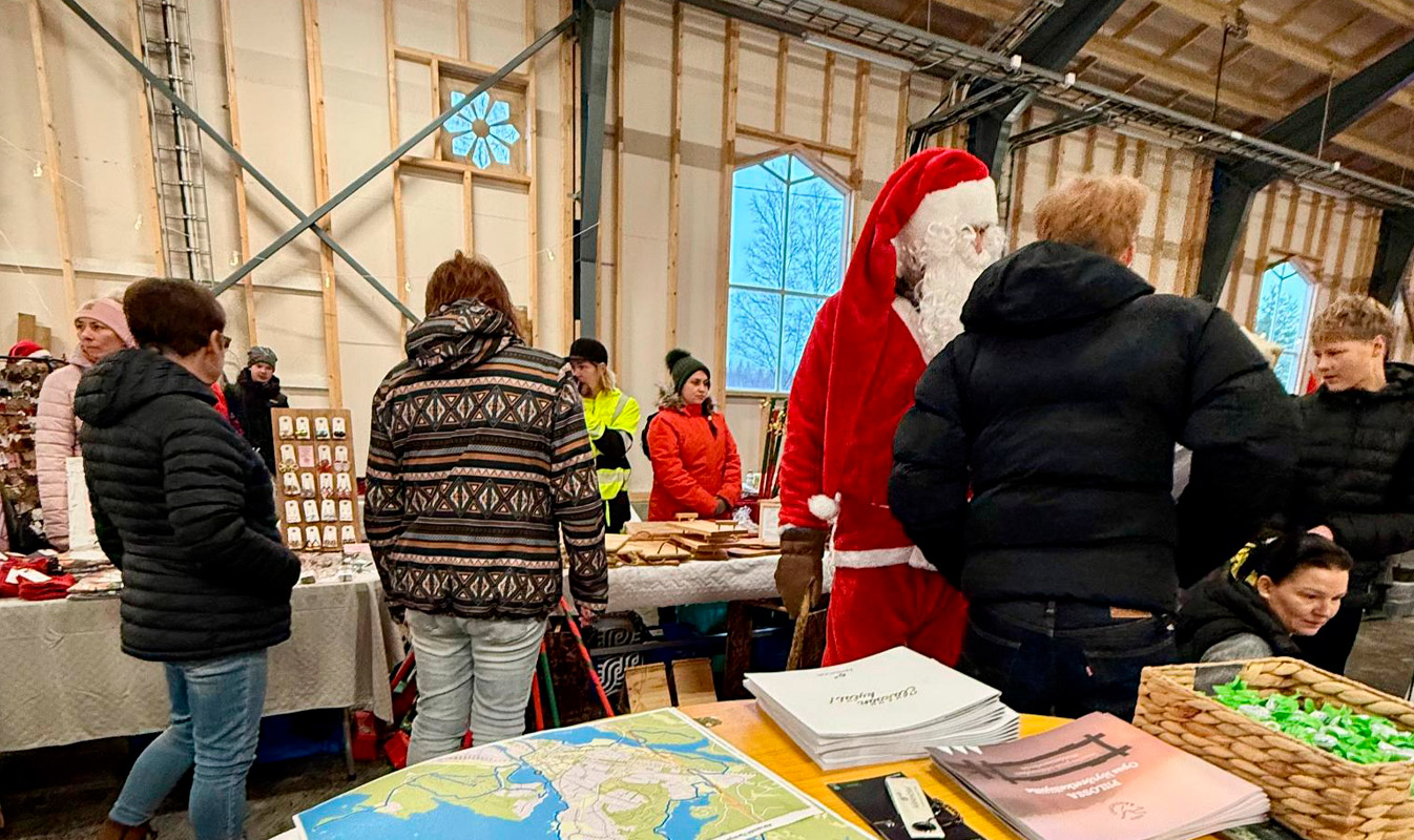 Kuva junatallista, jossa on myyntipöytiä ja ihmisiä. Etualalla hankkeen piste, jossa karttoja ja infoa Äänekoskesta.