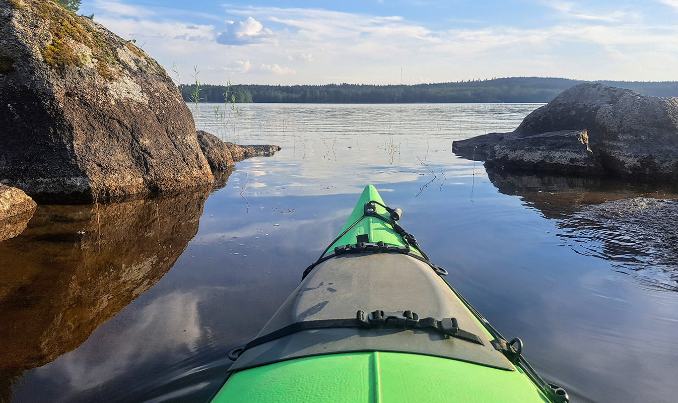 Kajakki järvellä, horisontissa metsää.