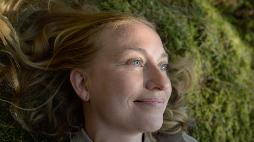 Nainen makaa sammaleella
