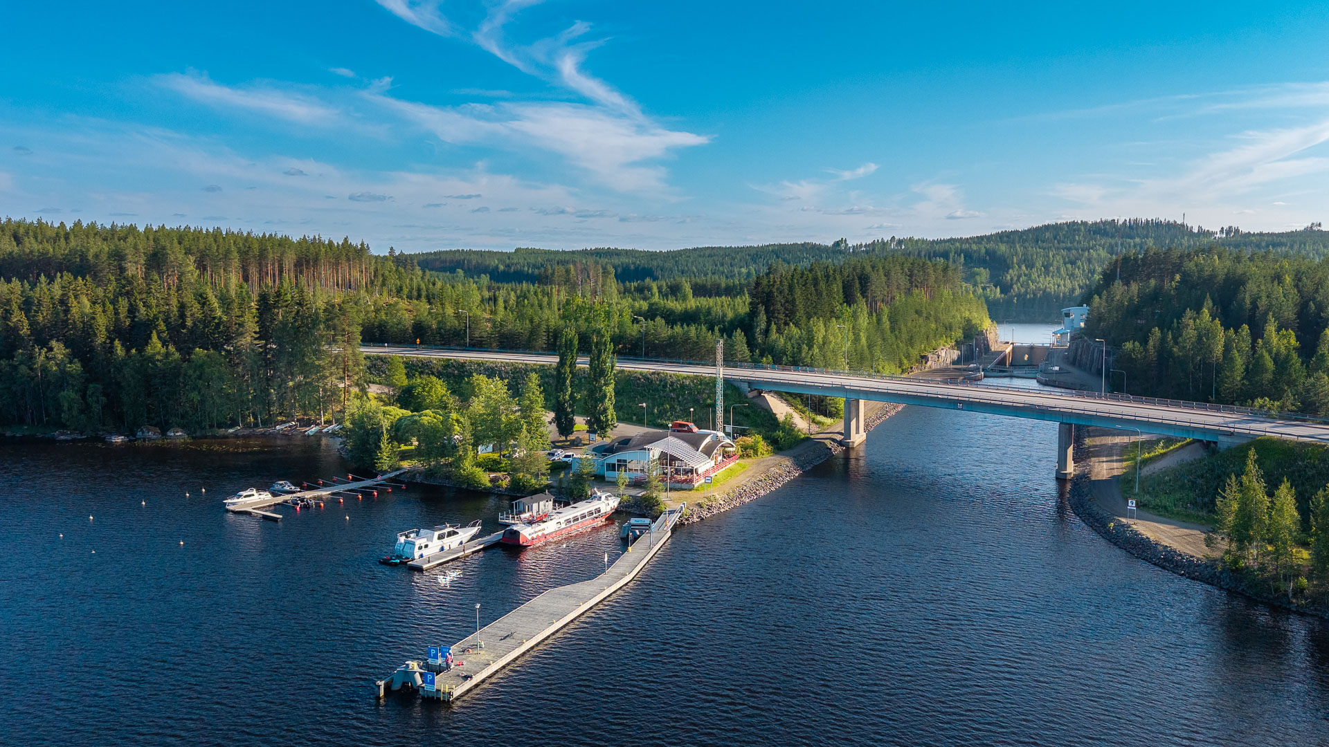 Kesäinen järvimaisema, jossa ravintolarakennus sekä sulku