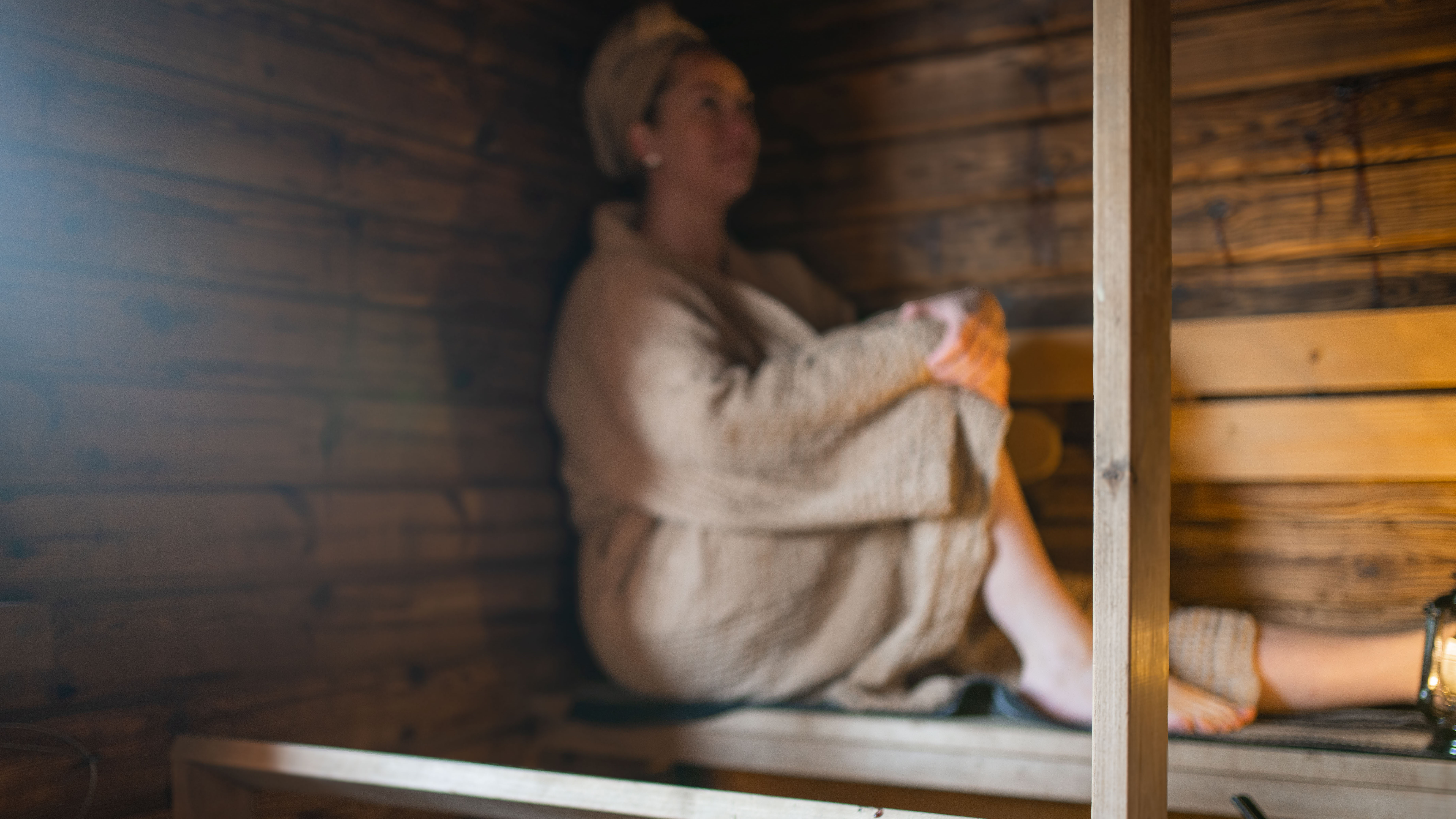 Henkilö istuu saunan lauteilla.