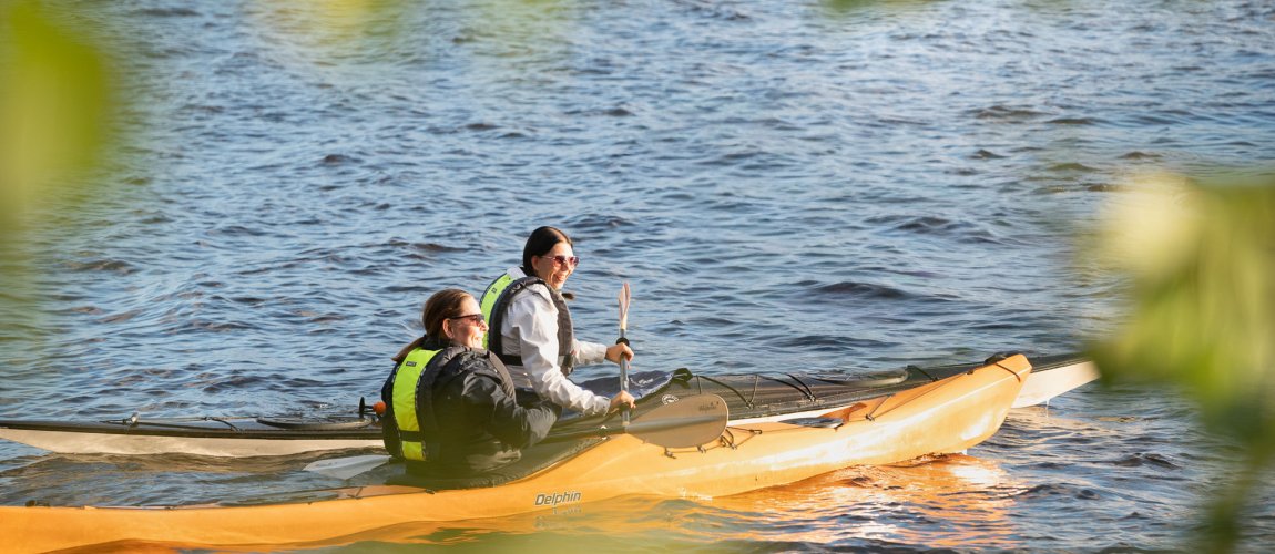 Kaksi henkilöä melomassa kajakeilla järvellä.