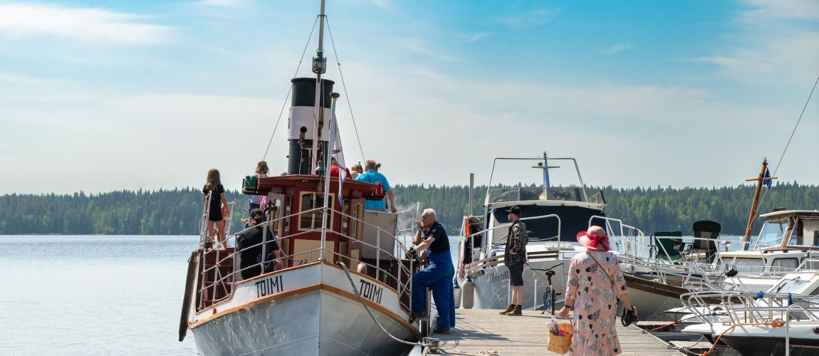 Toimi-laiva laiturissa ja ihmisiä nousee sen kyytiin.
