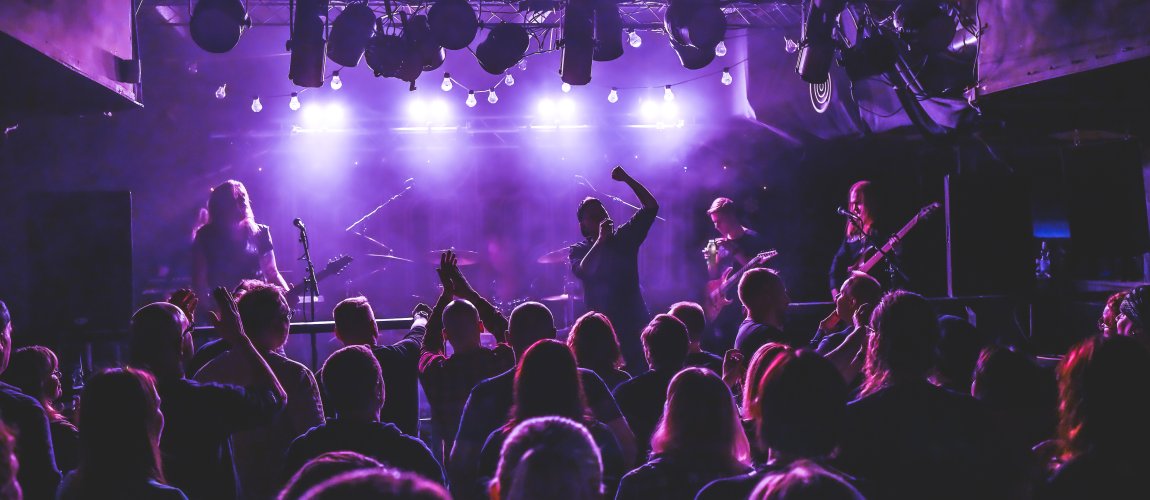 Bändi esiintyy lavalla ja osa yleisöstä nostaa käsiään ilmaan.