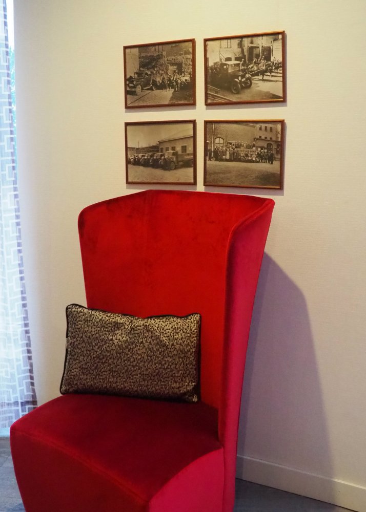 Kuva punaisesta nojatuolista sekä seinillä olevista tauluista.