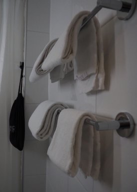 Kuva suihkutiloista, jossa suihkutangon päällä on pyyhkeitä.